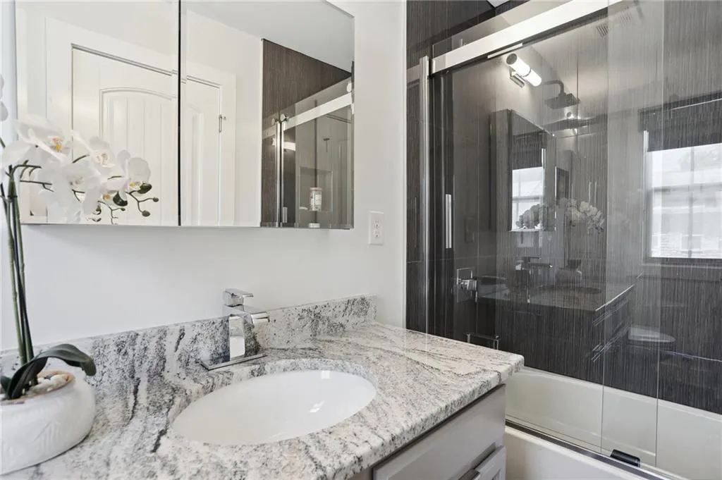 Bathroom attached to 2nd bedroom featuring enclosed tub / shower combo and vanity with extensive cabinet space