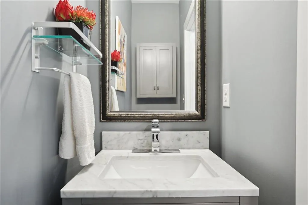 Renovated powder room featuring vanity with extensive cabinet space and marble top