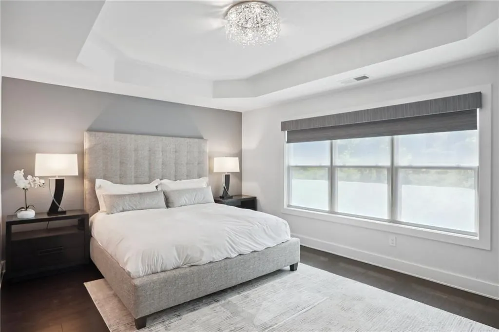 Primary Bedroom with a chandelier, a tray ceiling, and fossilized bamboo flooring