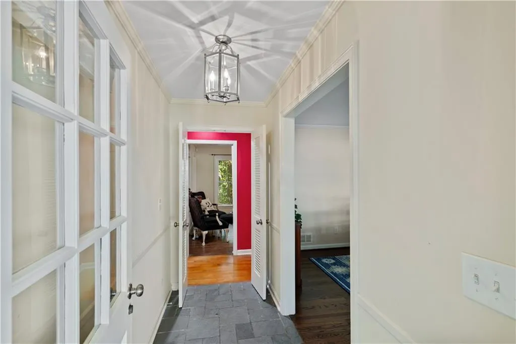 Hallway featuring a chandelier, crown molding, and dark stone finish floors