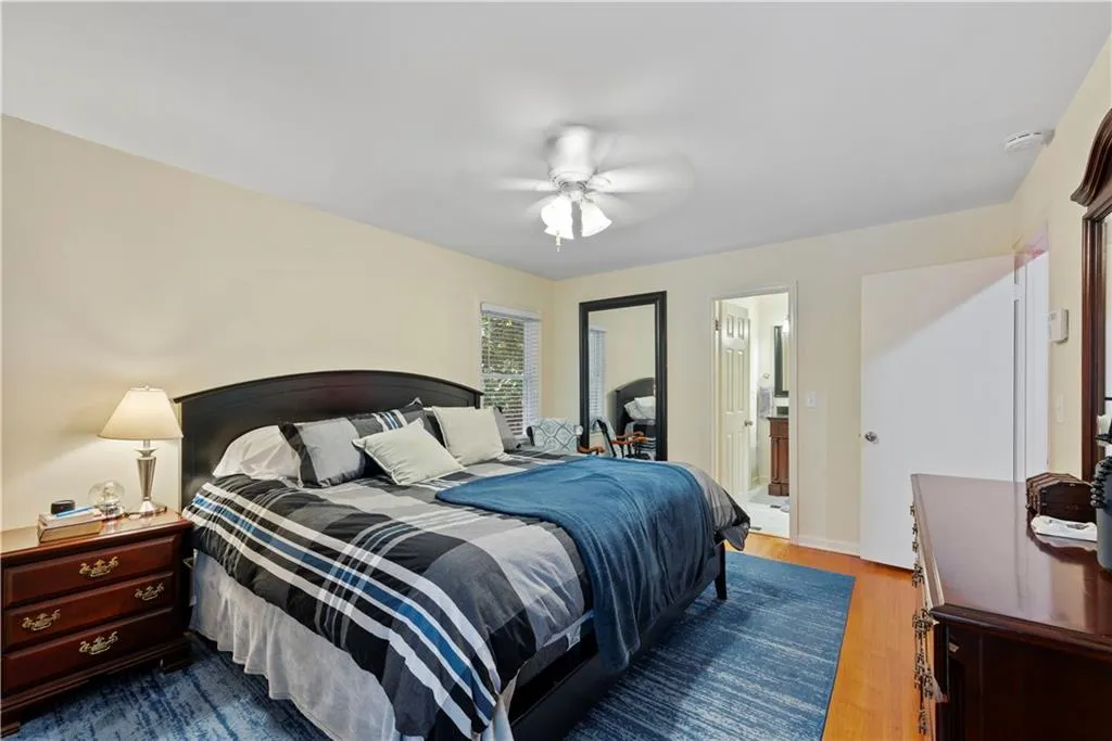 Bedroom with wood finished floors, a ceiling fan, and ensuite bath