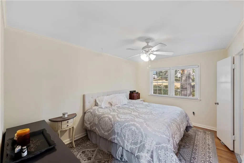 Bedroom with ornamental molding, wood finished floors, and ceiling fan