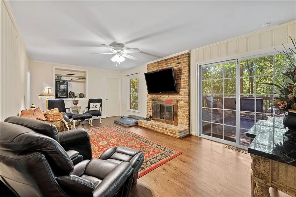 Living area with ornamental molding, wood finished floors, ceiling fan, and a fireplace