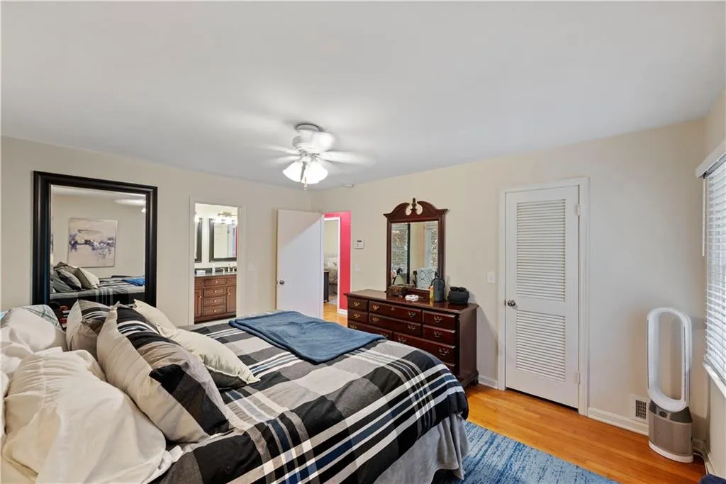 Bedroom featuring light wood-style floors, ensuite bath, a closet, and ceiling fan