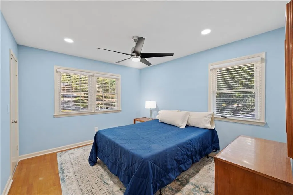 Bedroom with wood finished floors, a ceiling fan, multiple windows, and recessed lighting
