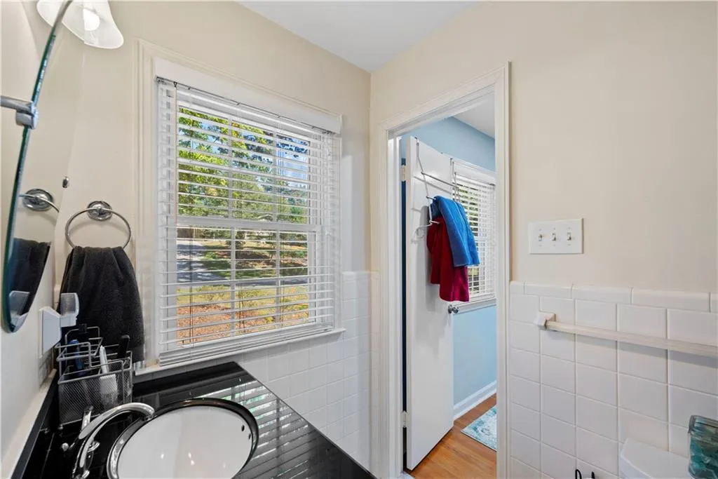 Bathroom with tile walls, plenty of natural light, vanity, wainscoting, and wood finished floors