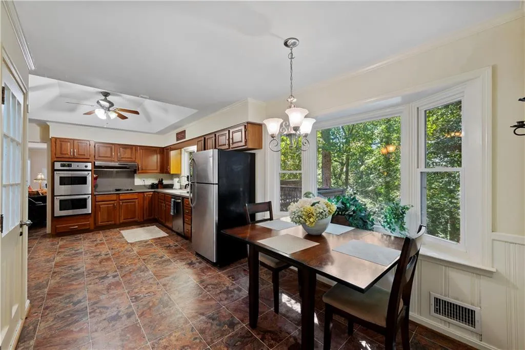 Kitchen featuring brown cabinets, stainless steel appliances, hanging light fixtures, a chandelier, and crown molding