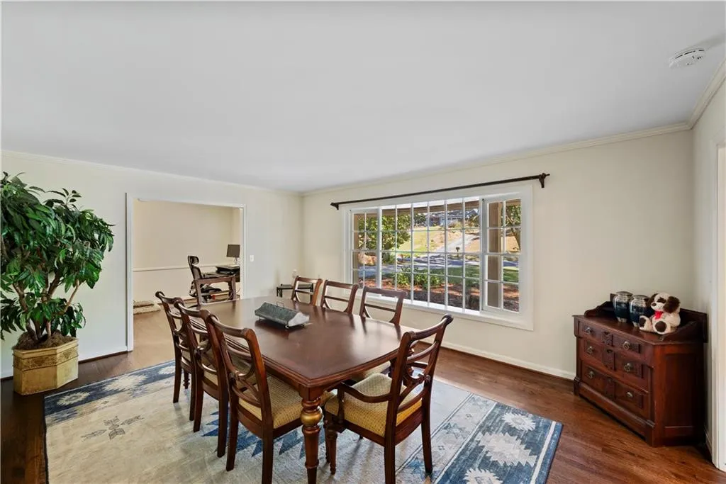 Dining space with ornamental molding and dark wood-type flooring