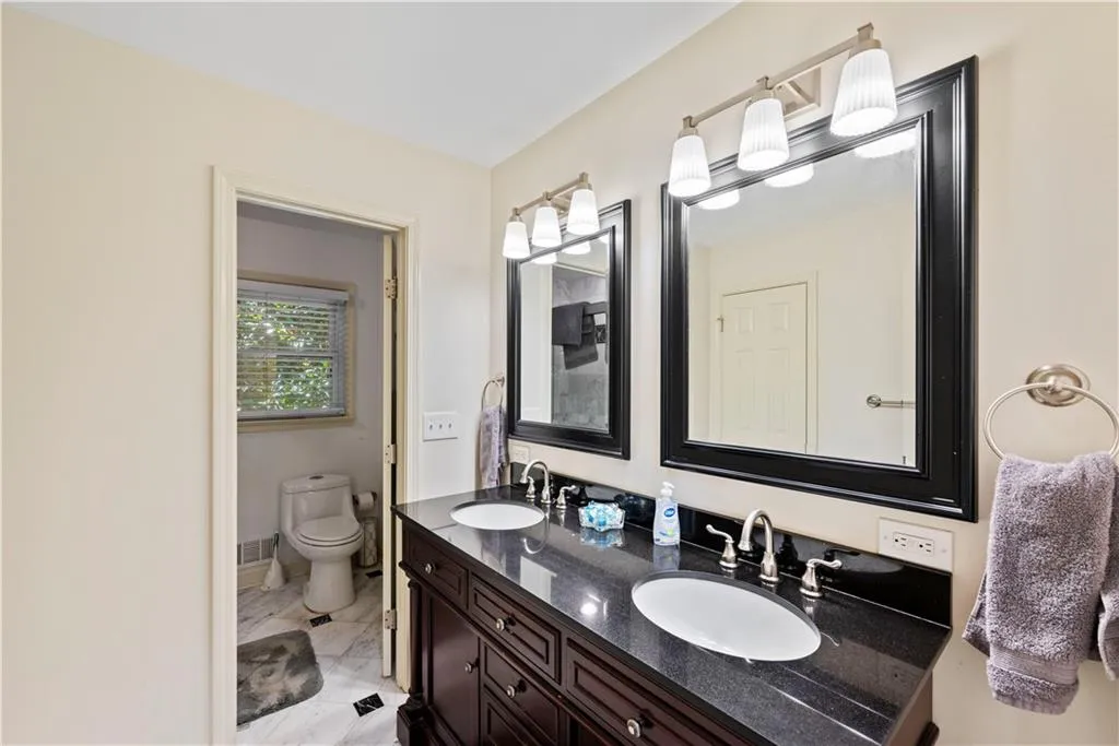 Full bathroom with double vanity and light marble finish flooring