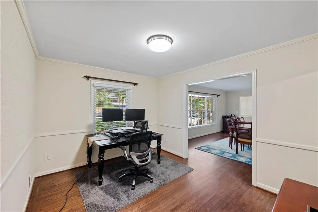 Home office with dark wood-style flooring, healthy amount of natural light, and ornamental molding