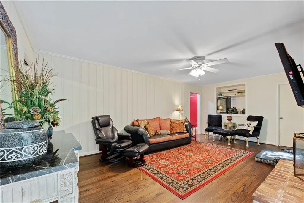 Living room with crown molding, dark wood-style flooring, and ceiling fan