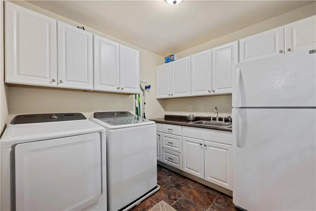 Washroom with washer and clothes dryer, dark stone finish floors, and cabinet space