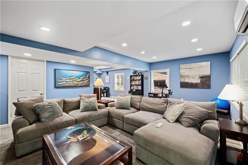 Living room with carpet, a wall mounted AC, and recessed lighting