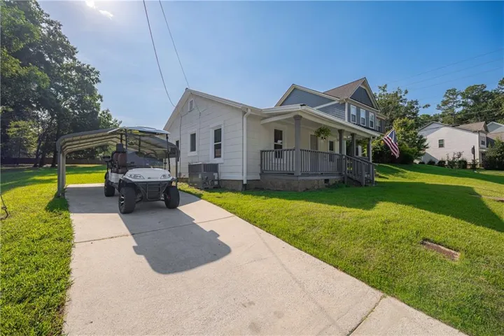 Two-story residence with a gray-painted front porch, a concrete driveway, and an attached metal carport