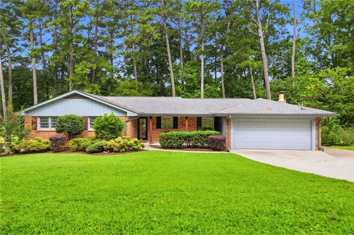Brick facade with light blue siding, an attached garage, and a concrete driveway