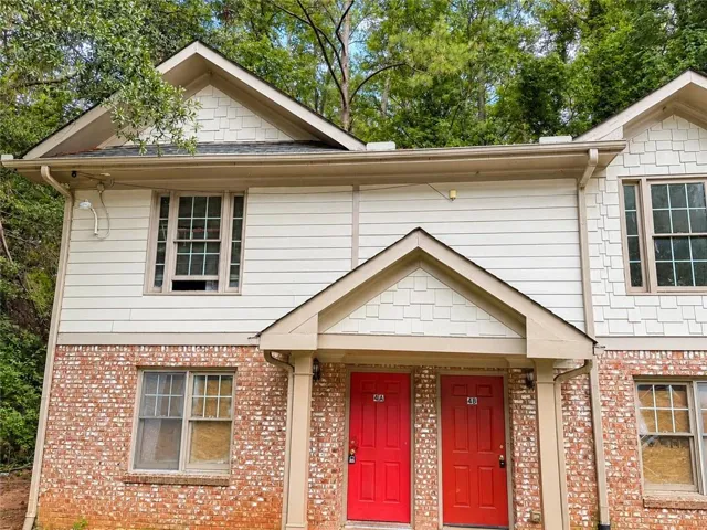 Two-story exterior with horizontal siding and shingle accents, red brick lower facade, and dual covered entryways
