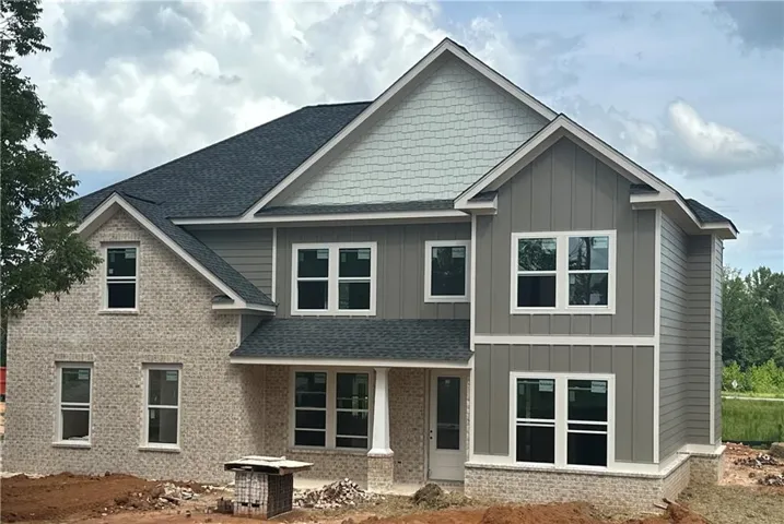 Two-story home with a multi-textured facade featuring light brick, vertical siding, and horizontal siding