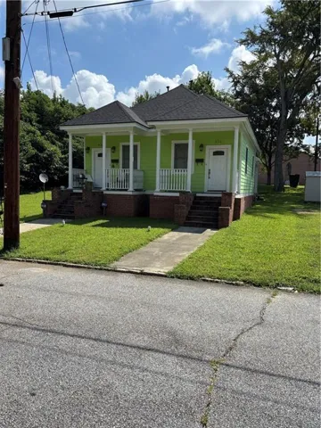 Duplex property featuring a vibrant green exterior, white trim, and a dark shingle roof