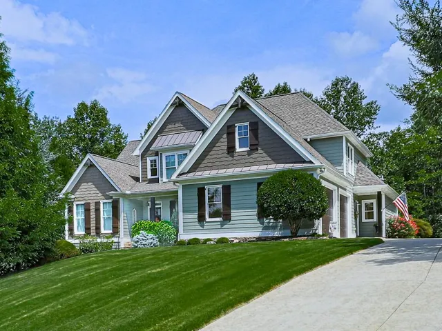 Multi-level residence featuring a pitched roof, shingle siding, and dormer windows