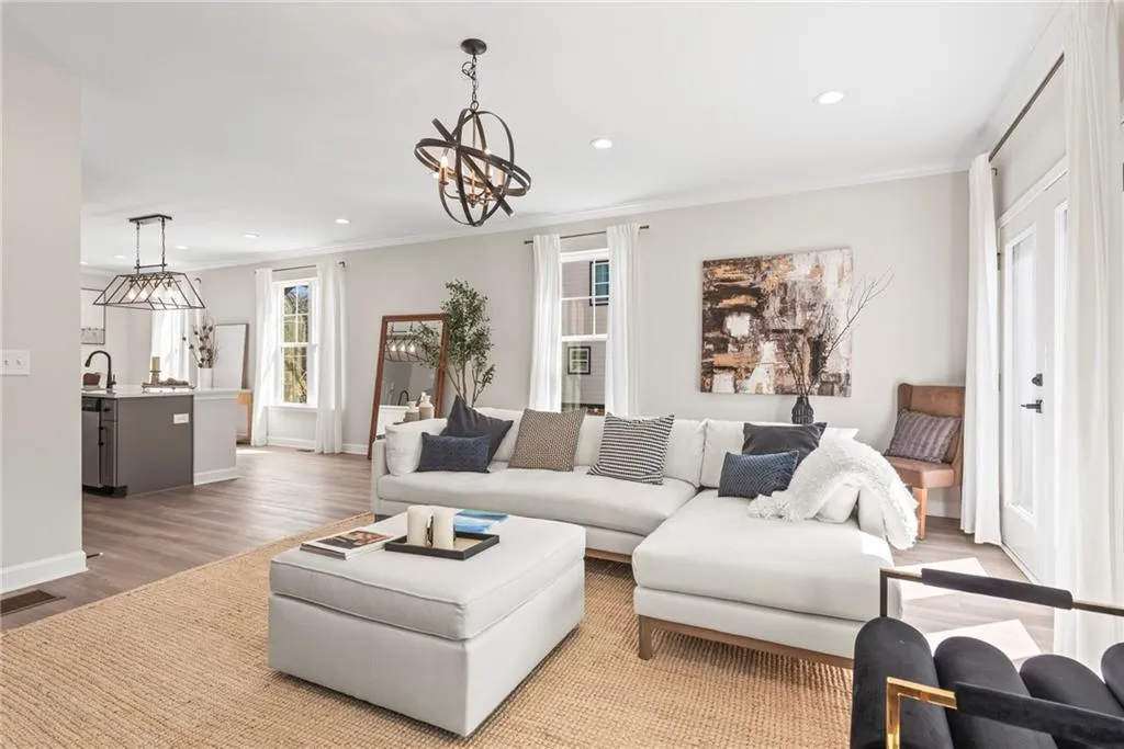 Living room featuring wood finished floors, recessed lighting, ornamental molding, and a chandelier