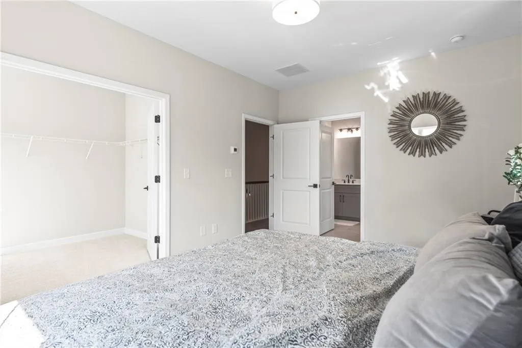 Bedroom featuring light carpet, a spacious closet, and connected bathroom