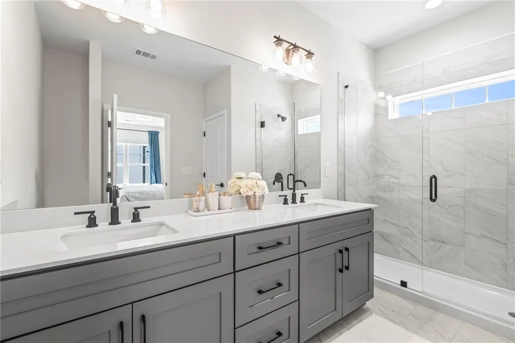 Full bathroom with connected bathroom, double vanity, and a shower stall