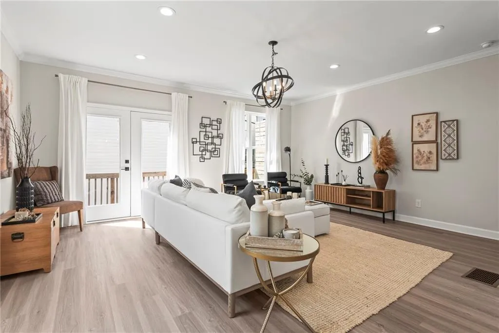 Living area featuring wood finished floors, crown molding, recessed lighting, french doors, and a chandelier