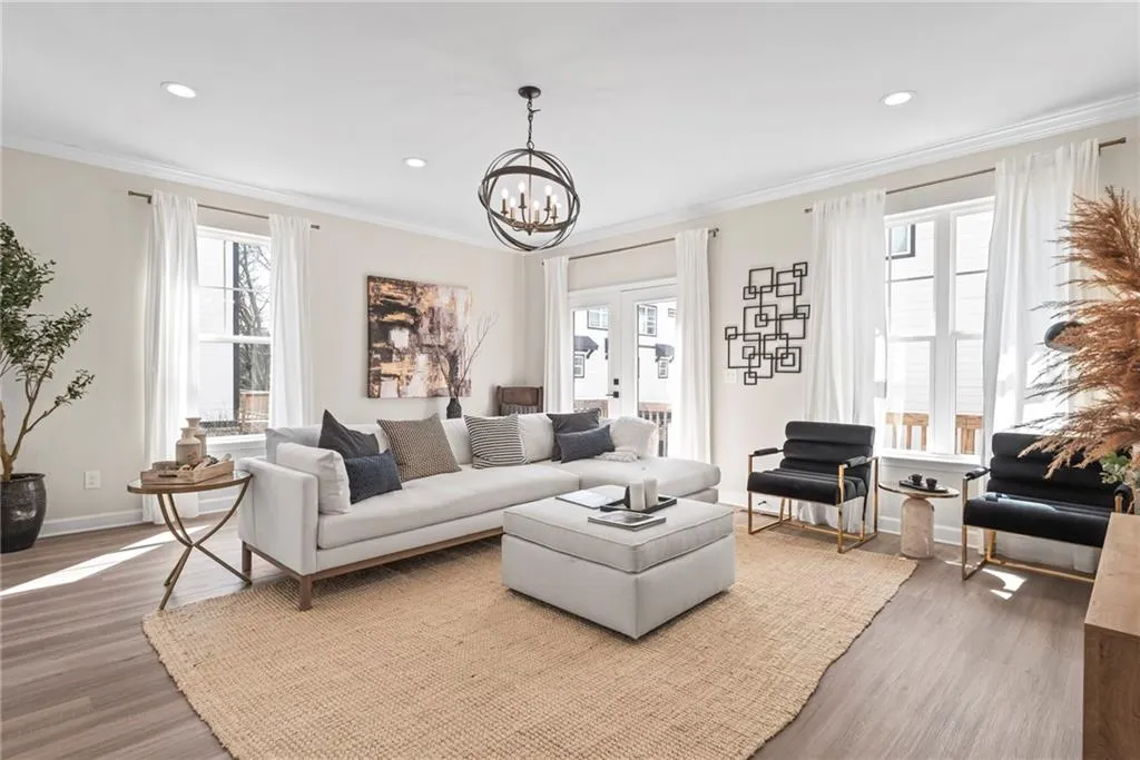 Living area featuring ornamental molding, healthy amount of natural light, wood finished floors, recessed lighting, and a chandelier