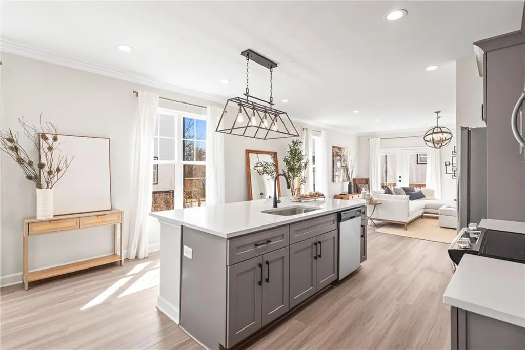 Kitchen with gray cabinets, light wood finished floors, pendant lighting, recessed lighting, and open floor plan
