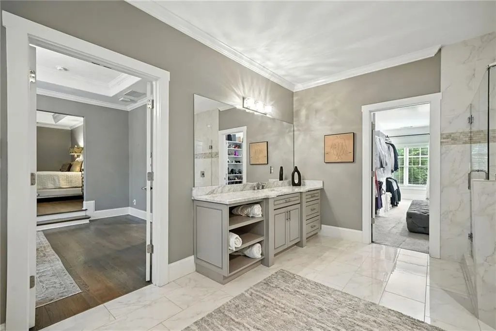 Bathroom featuring ensuite bathroom, vanity, light marble finish flooring, and crown molding