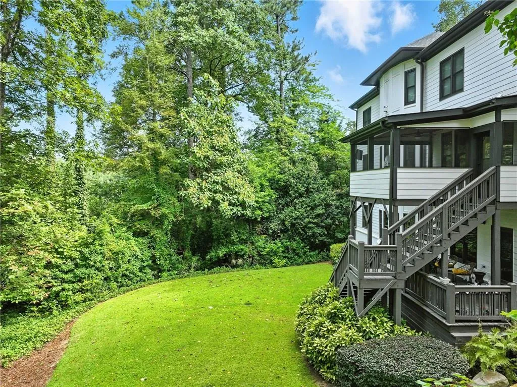 View of grassy yard with a sunroom and stairway