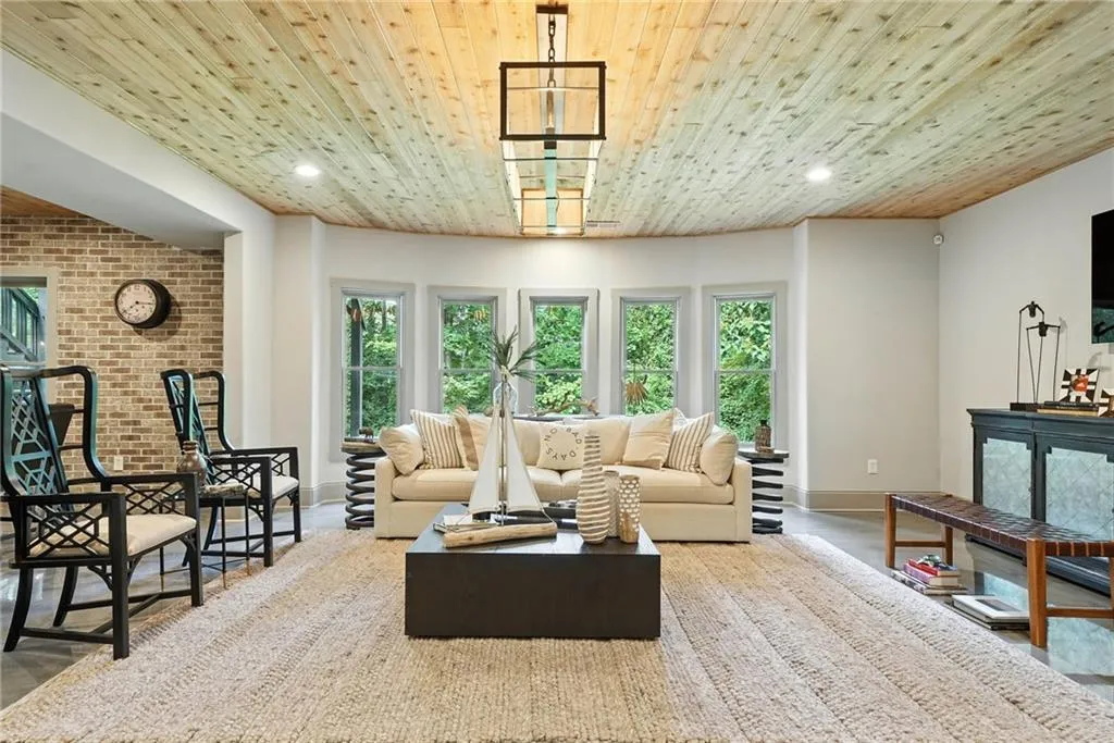 Living area with wood ceiling, plenty of natural light, recessed lighting, and brick wall