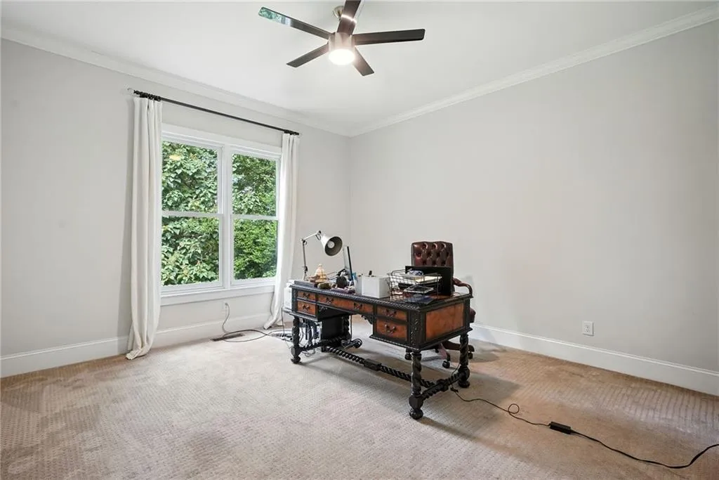 Carpeted office featuring ornamental molding and a ceiling fan