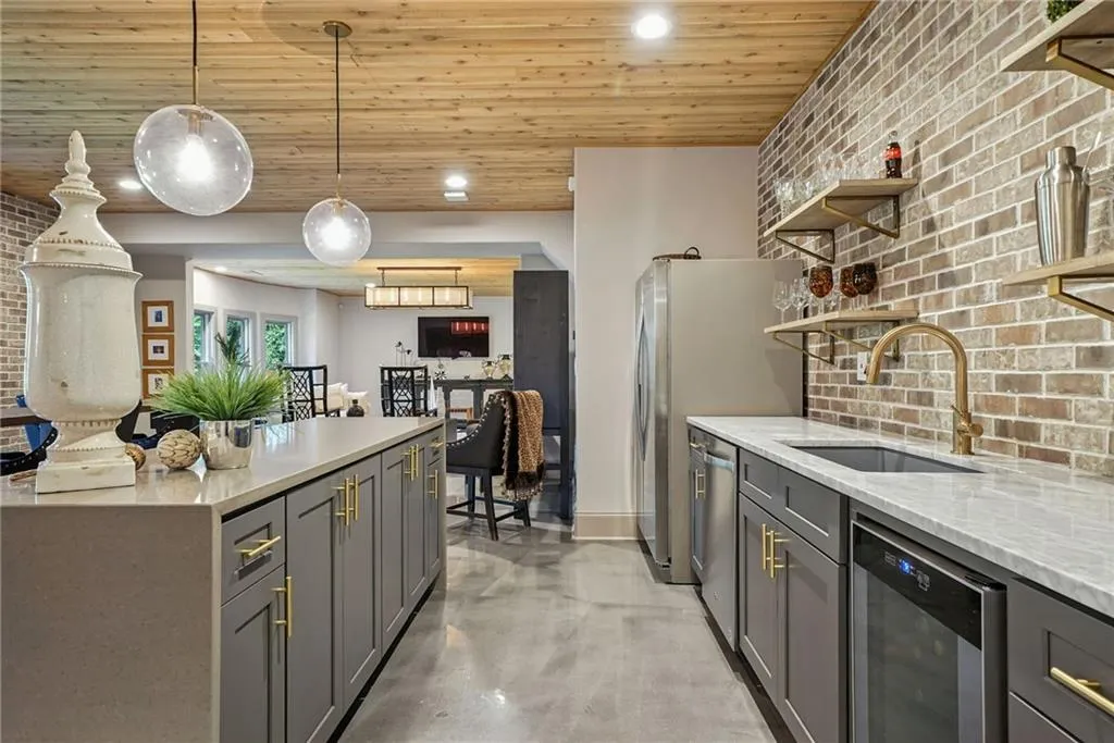 Kitchen with brick wall, light stone counters, open shelves, hanging light fixtures, and wooden ceiling