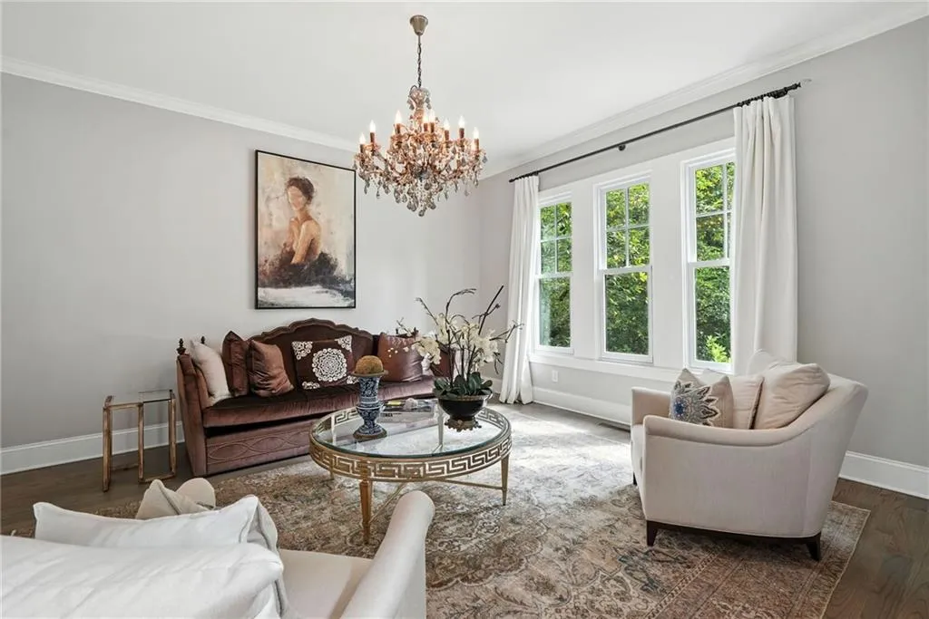 Living area with wood finished floors, crown molding, and a chandelier
