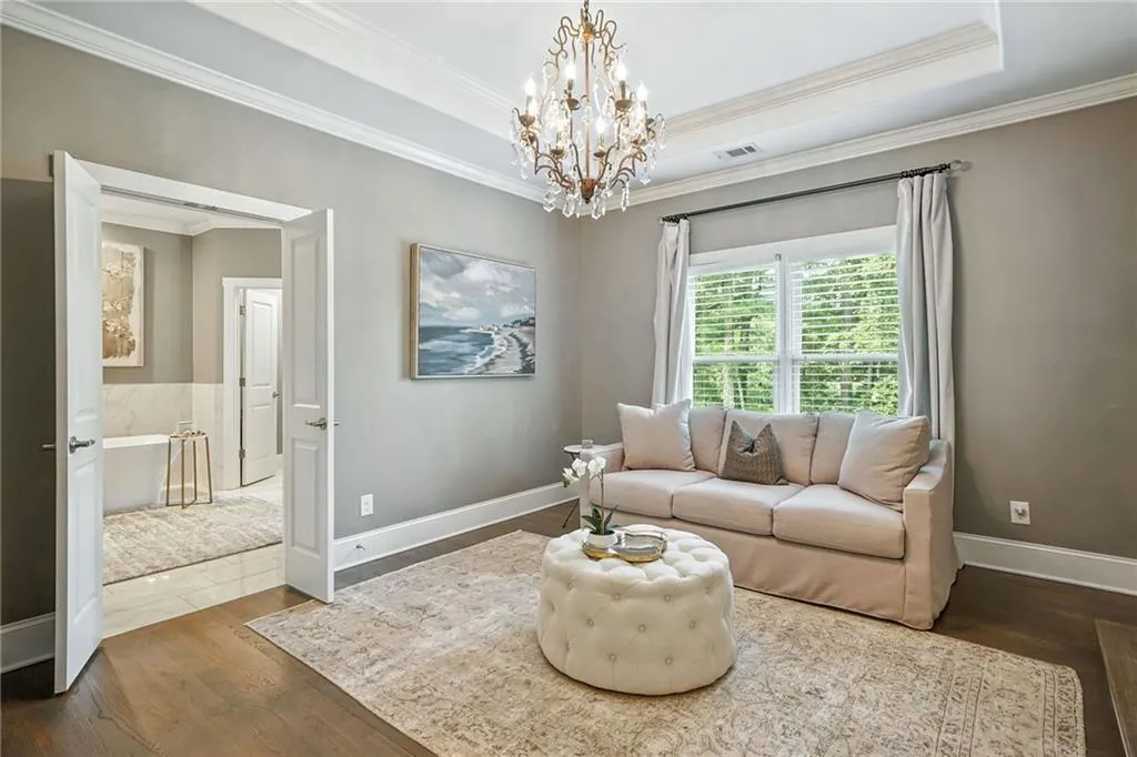 Sitting room featuring a tray ceiling, crown molding, a chandelier, and dark wood-style floors