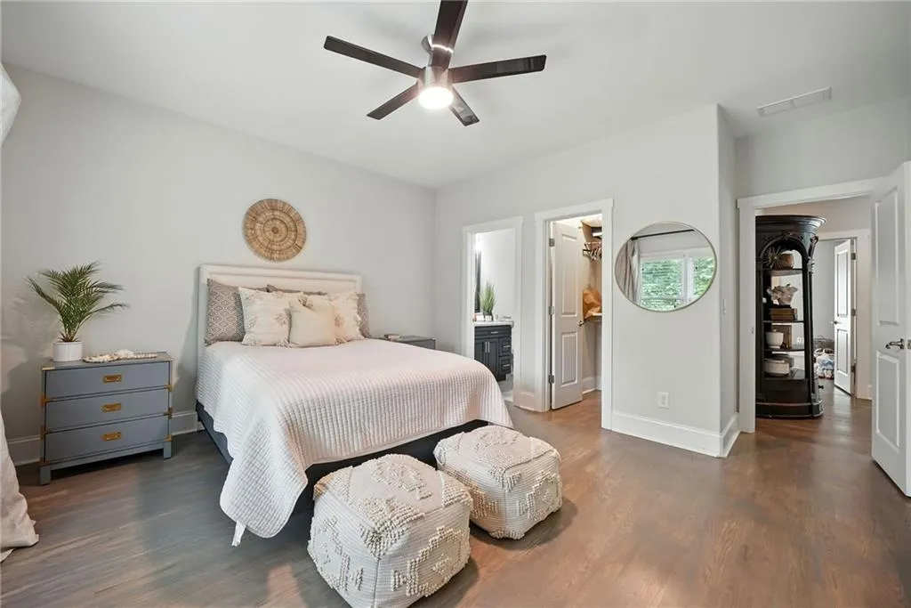 Bedroom with wood finished floors, a spacious closet, a ceiling fan, and ensuite bath