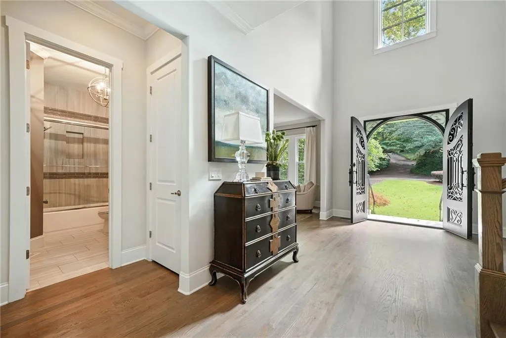 Entrance foyer with wood finished floors, a chandelier, ornamental molding, and a high ceiling