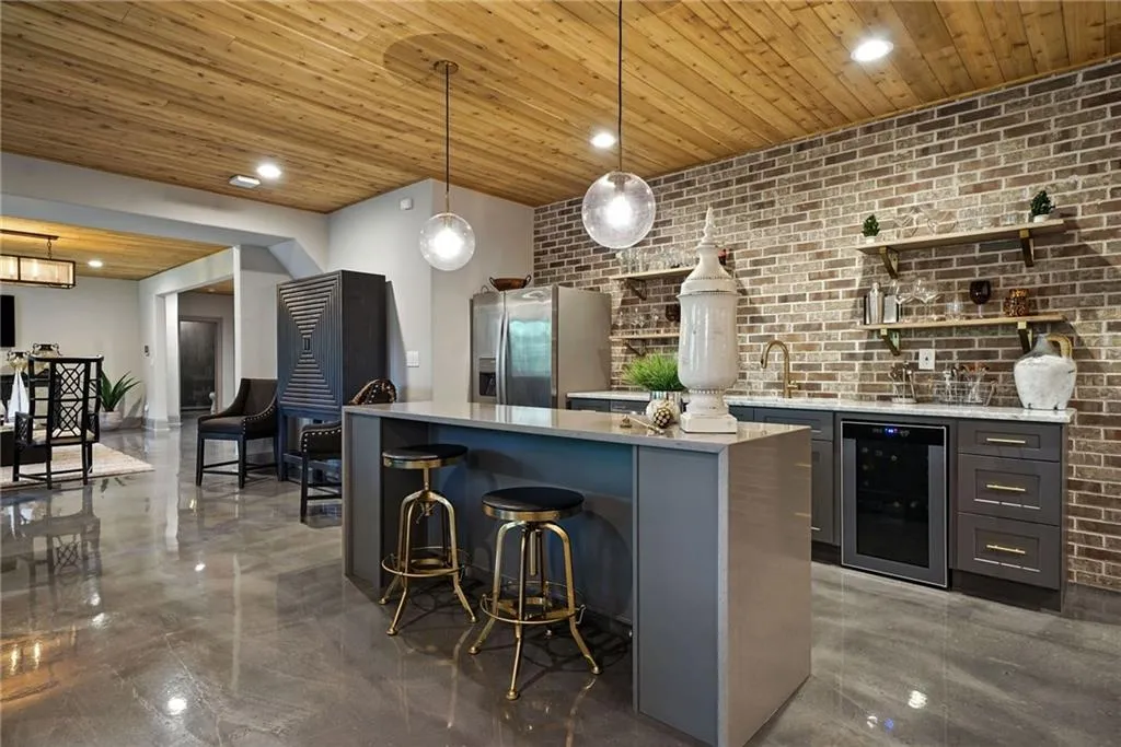 Kitchen with open shelves, brick wall, a breakfast bar area, light stone countertops, and recessed lighting