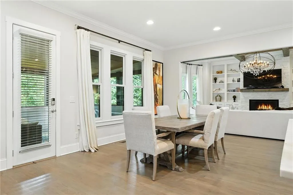 Dining space with crown molding, a warm lit fireplace, light wood-style flooring, a chandelier, and recessed lighting