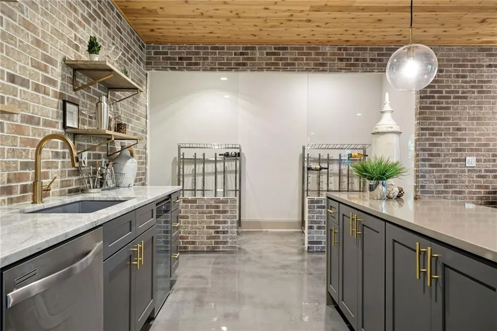 Kitchen with brick wall, open shelves, pendant lighting, dishwasher, and light stone counters