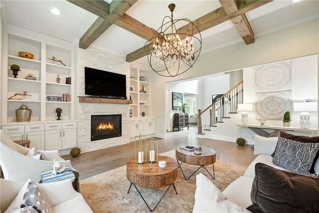 Living area featuring beamed ceiling, wood finished floors, a fireplace, built in shelves, and stairs