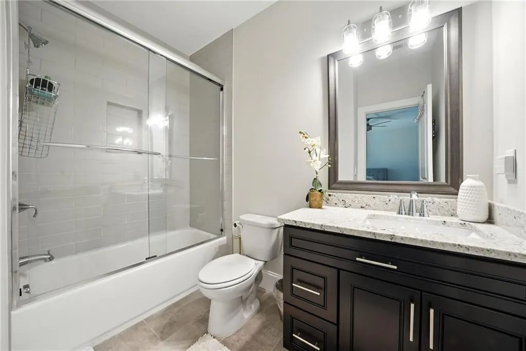 Bathroom featuring combined bath / shower with glass door, vanity, and light tile patterned floors