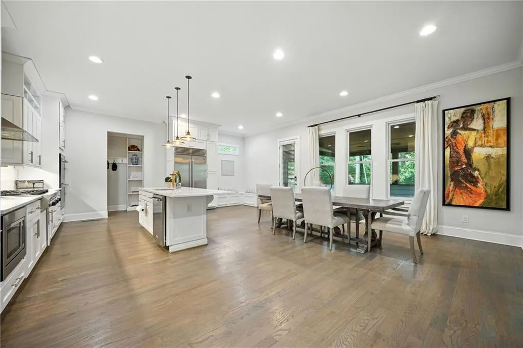Kitchen featuring decorative light fixtures, white cabinets, dark wood-style floors, recessed lighting, and a center island with sink