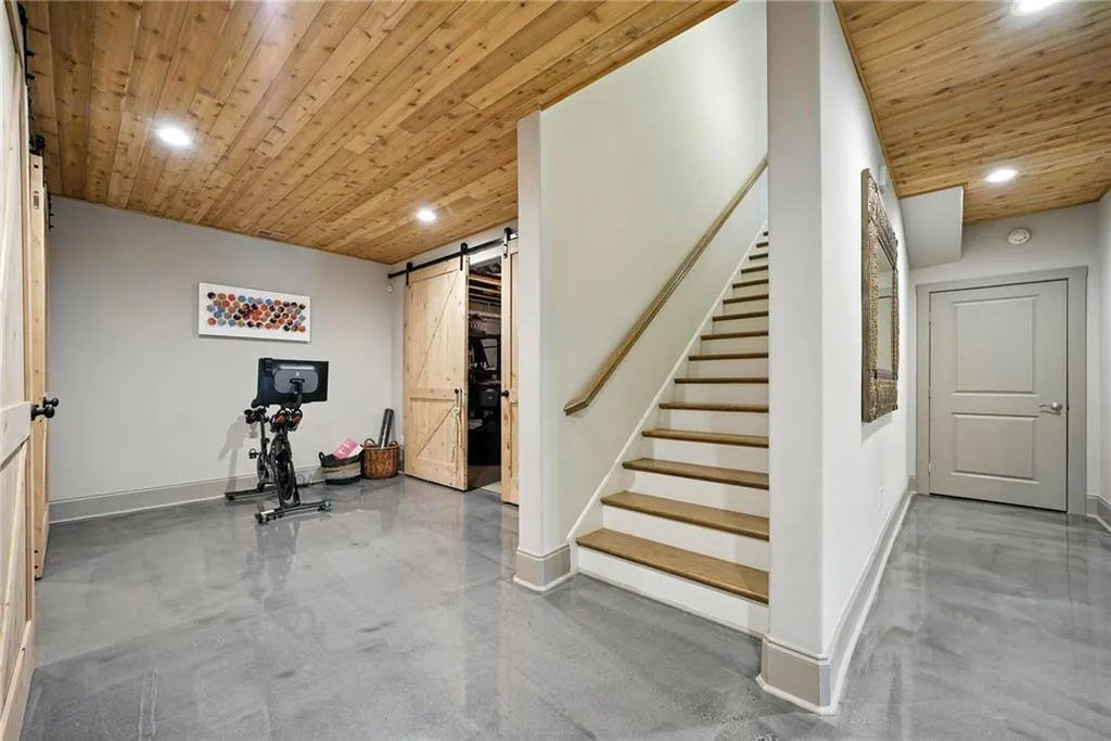 Basement featuring a barn door, recessed lighting, wood ceiling, and stairs