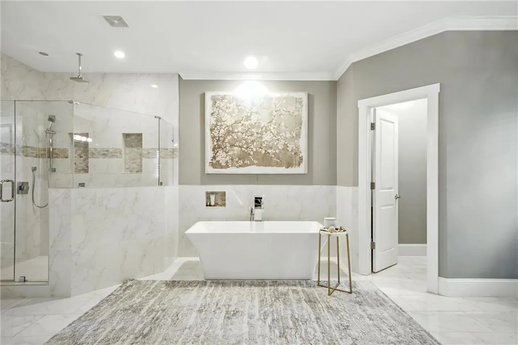 Bathroom featuring a marble finish shower, light marble finish flooring, a soaking tub, recessed lighting, and ornamental molding
