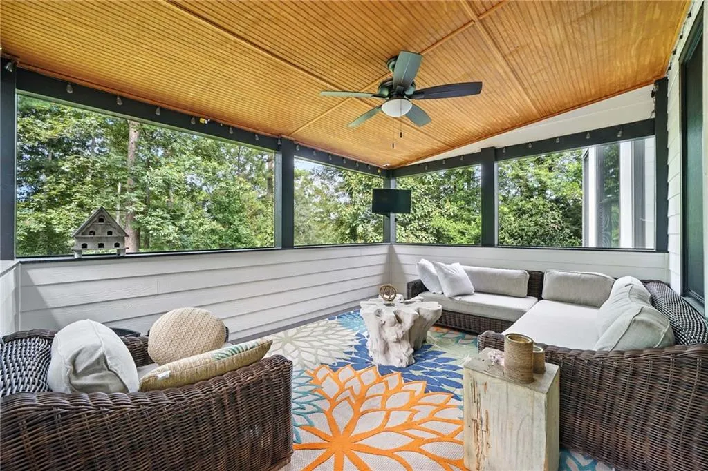 Sunroom / solarium with ceiling fan, an outdoor hangout area, wood ceiling, lofted ceiling, and view of scattered trees