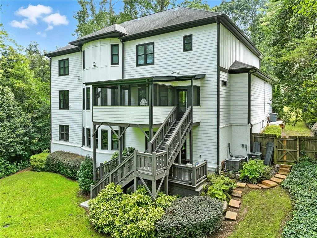 Rear view of property with stairway, a sunroom, a yard, a deck, and roof with shingles
