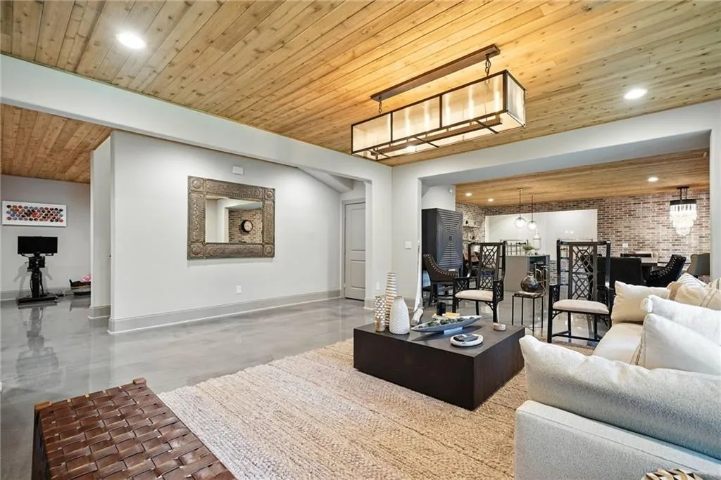 Living room with recessed lighting, wooden ceiling, finished concrete flooring, and brick wall