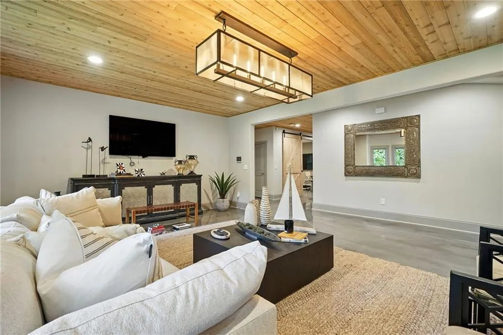 Living room with a barn door, wood ceiling, recessed lighting, and finished concrete floors